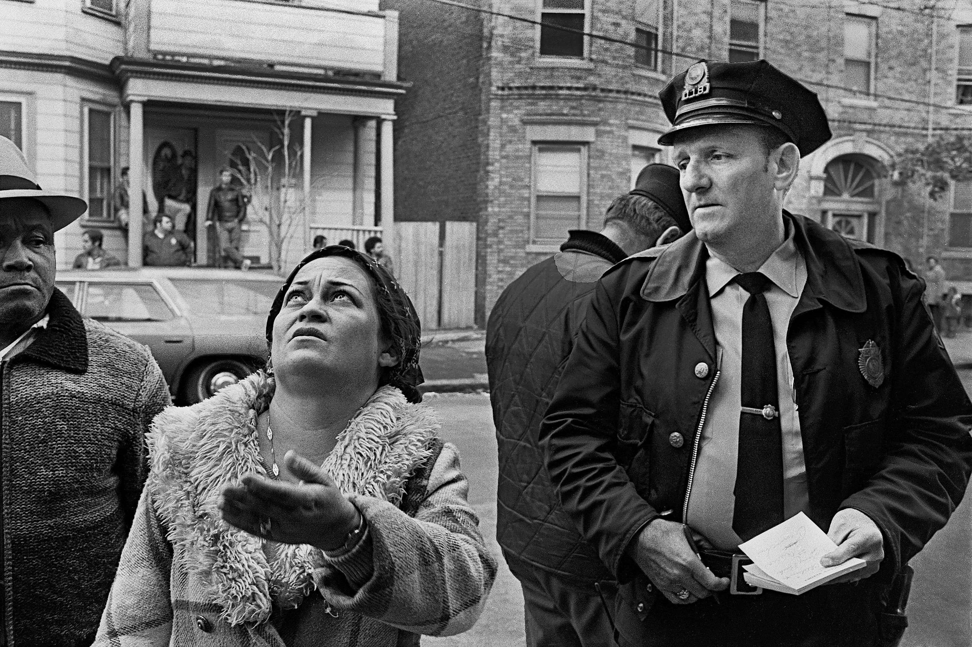 Black-and-white photograph of Officer Sullivan and Chelsea residents looking upward at a fire on Chestnut Street.