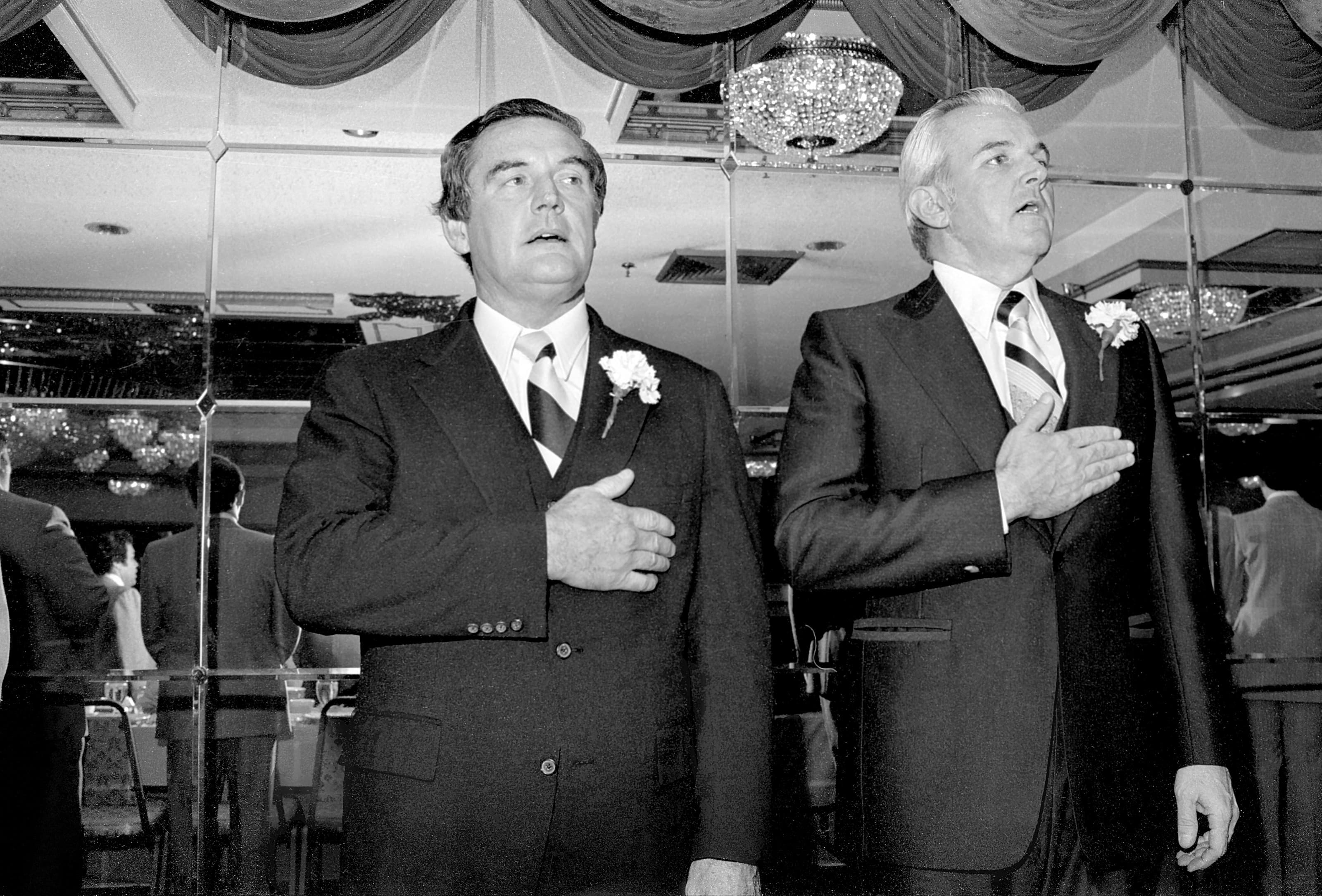 Black-and-white photograph of Governor Edward J. King and State Senator Francis D. Doris standing with hands over their hearts in Chelsea.