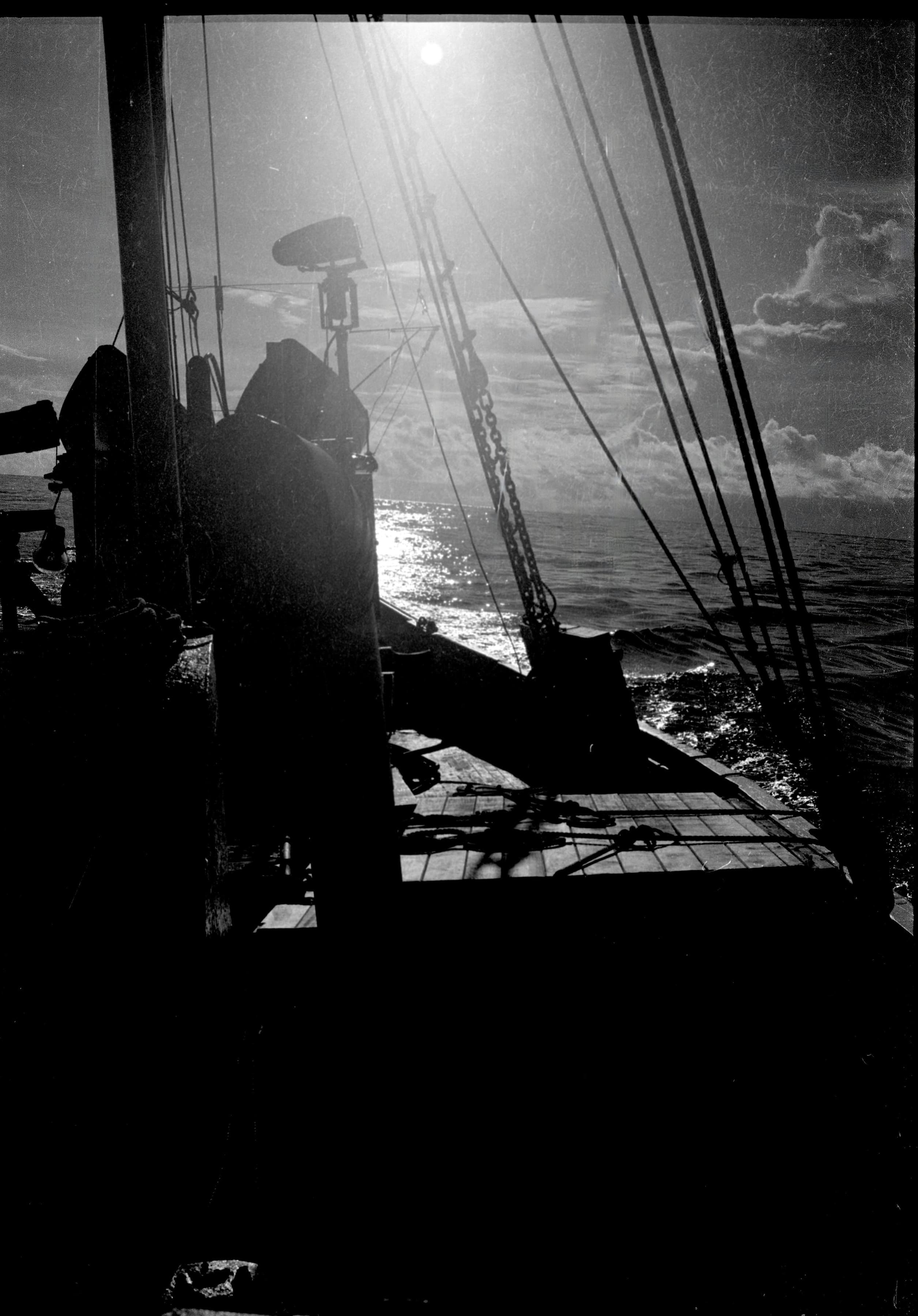 Black-and-white photograph from aboard the Lady of Good Voyage underway toward Honduras, with rigging silhouetted against the sun and sea.