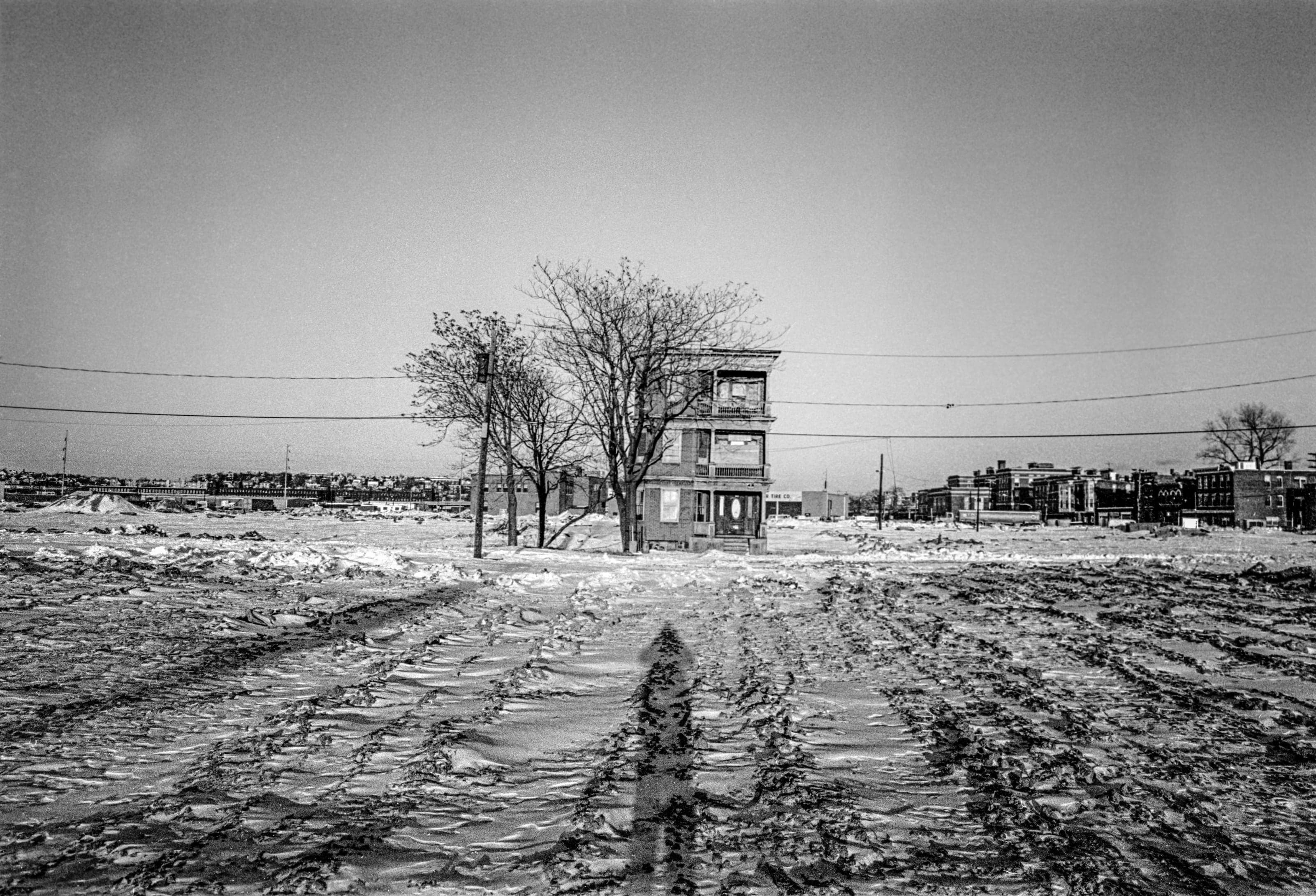Black-and-white photograph of a lone triple-decker standing in a broad snow-covered cleared area on Third Street in Chelsea.