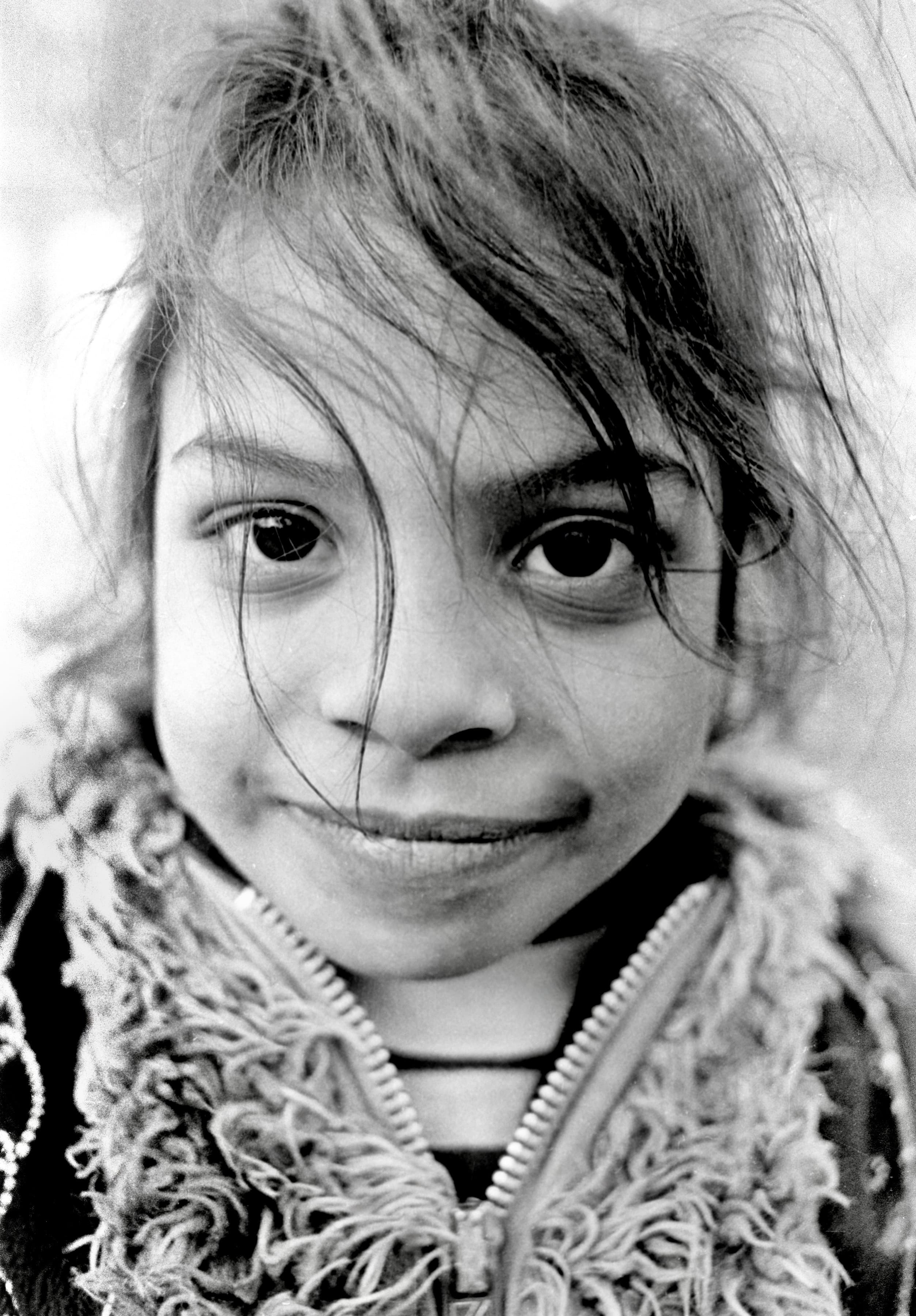 Black-and-white close portrait of a young girl in Polonia Park looking directly at the camera.