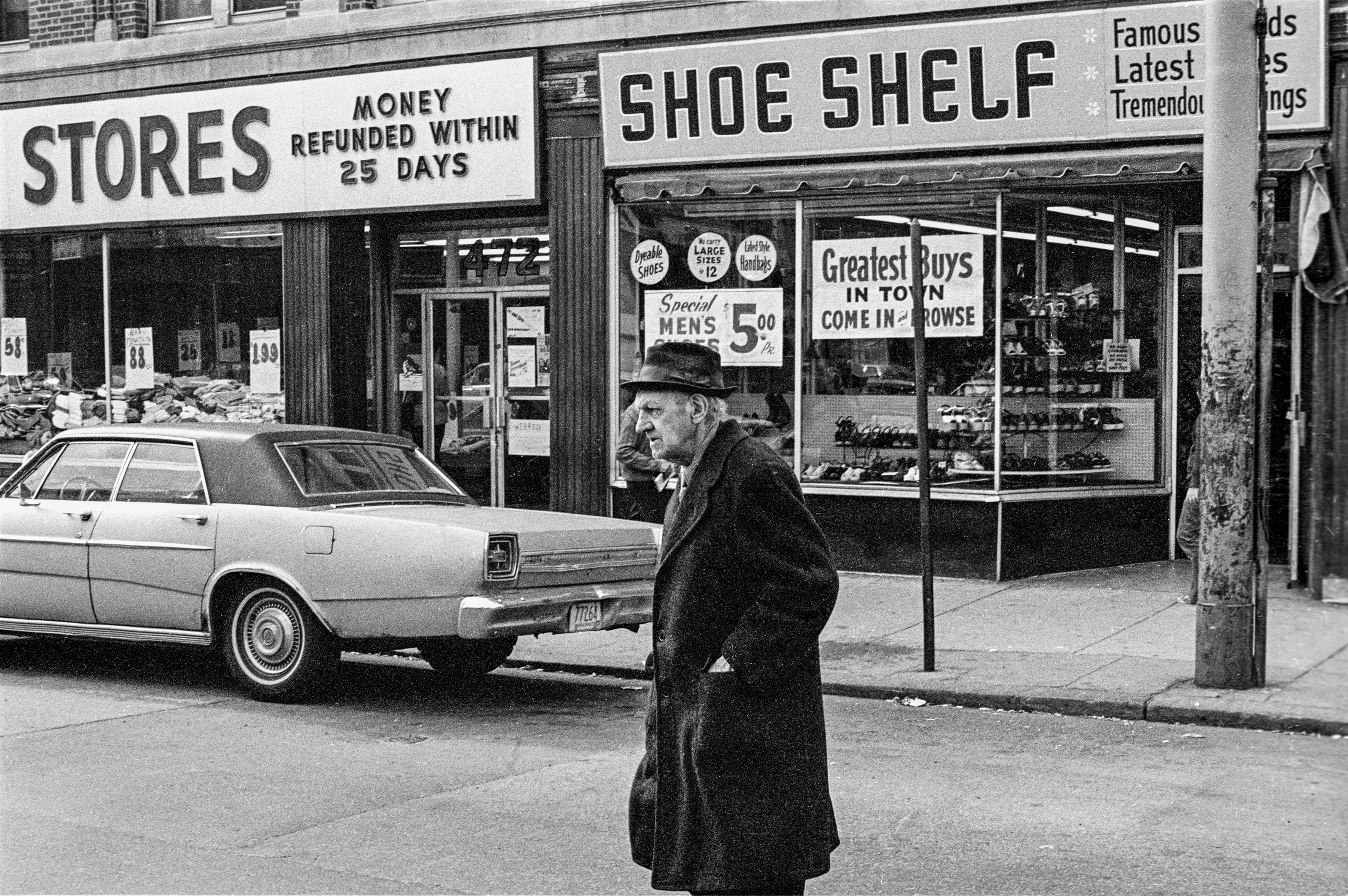 Black-and-white street photograph of a man outside the Shoe Shelf storefront in Chelsea.