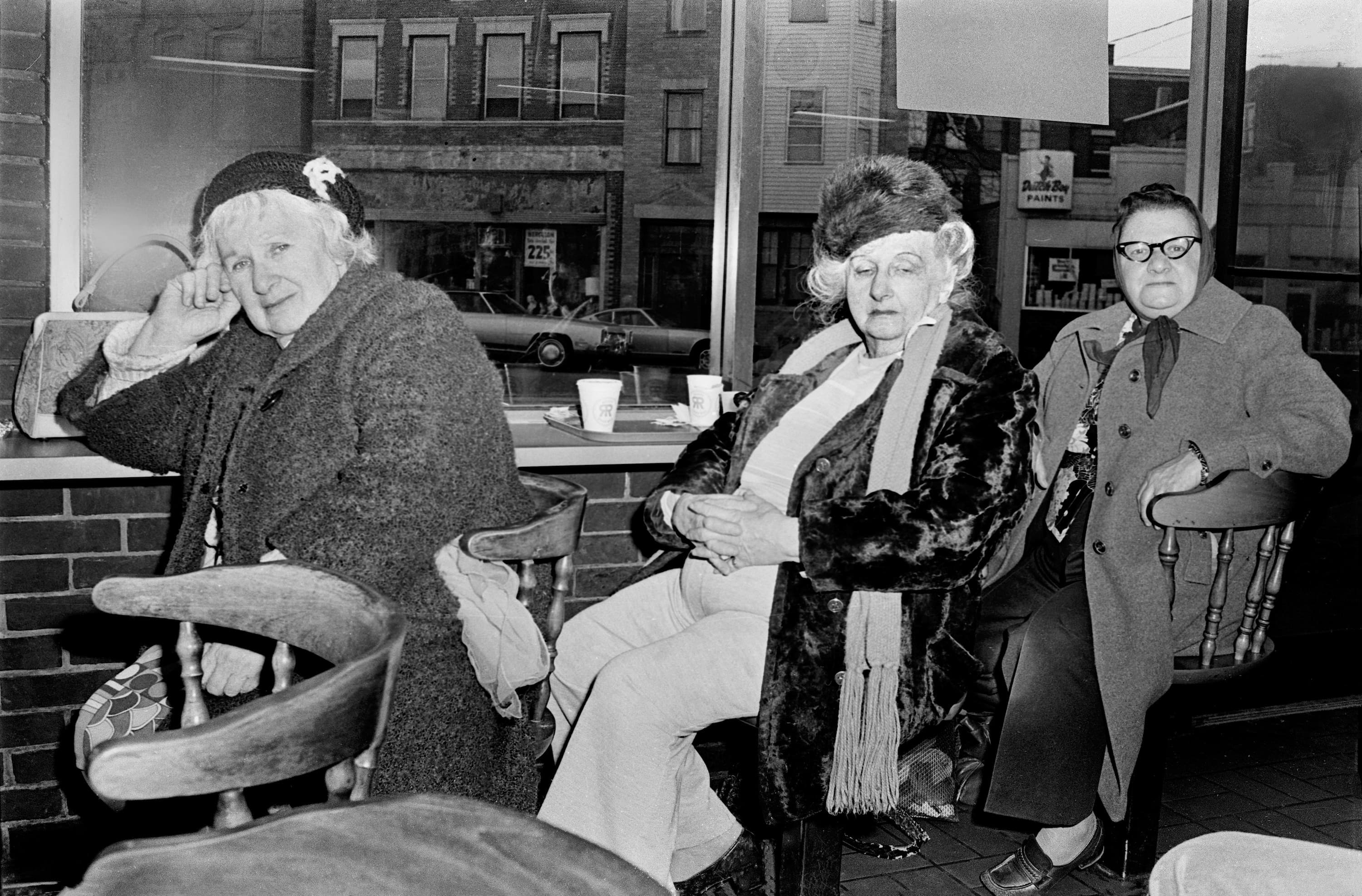 Black-and-white photograph of three women seated together at the counter at Riley's Roast Beef in Chelsea.