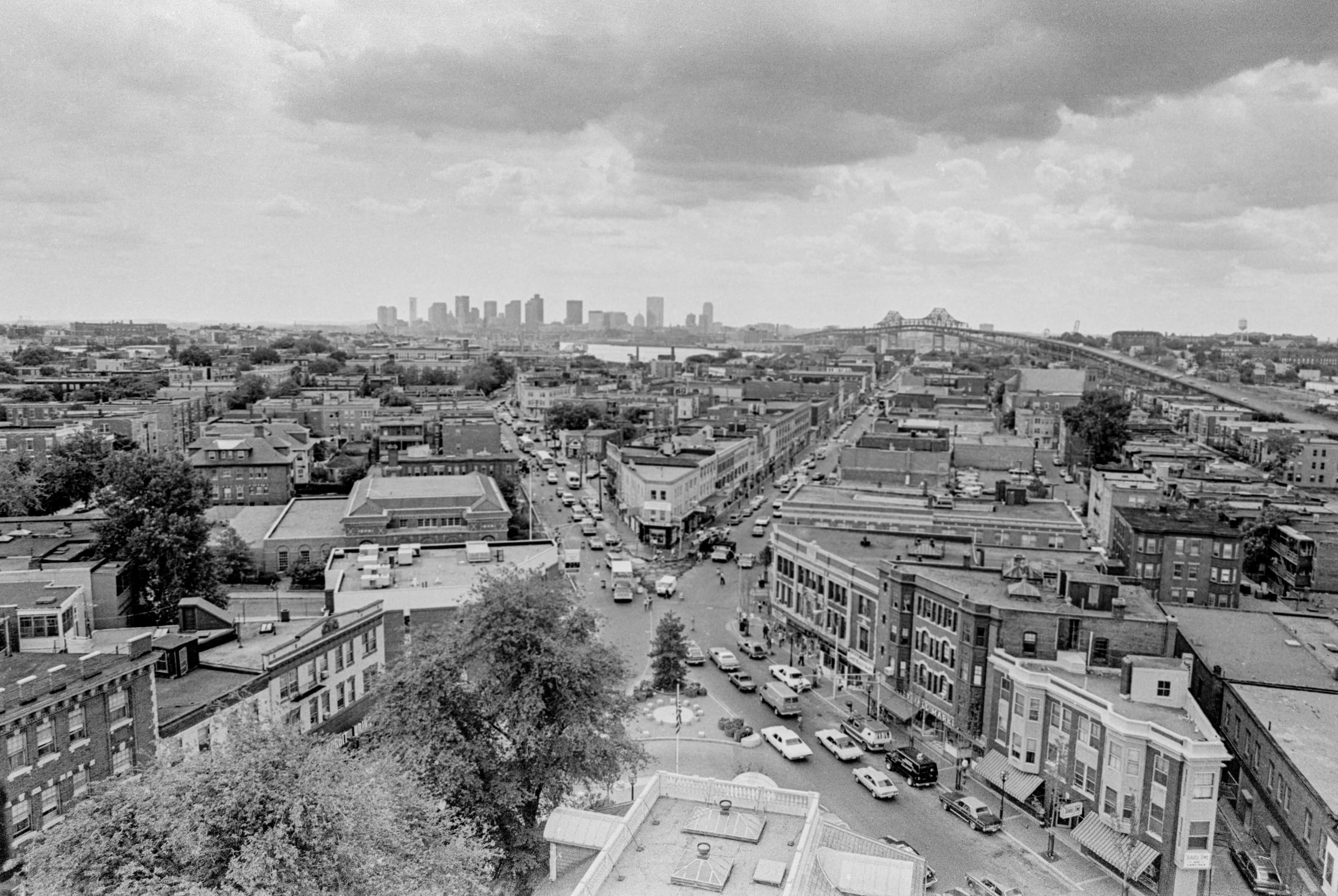 Black-and-white panoramic view over Chelsea from the City Hall spire, with Broadway leading toward the Boston skyline.