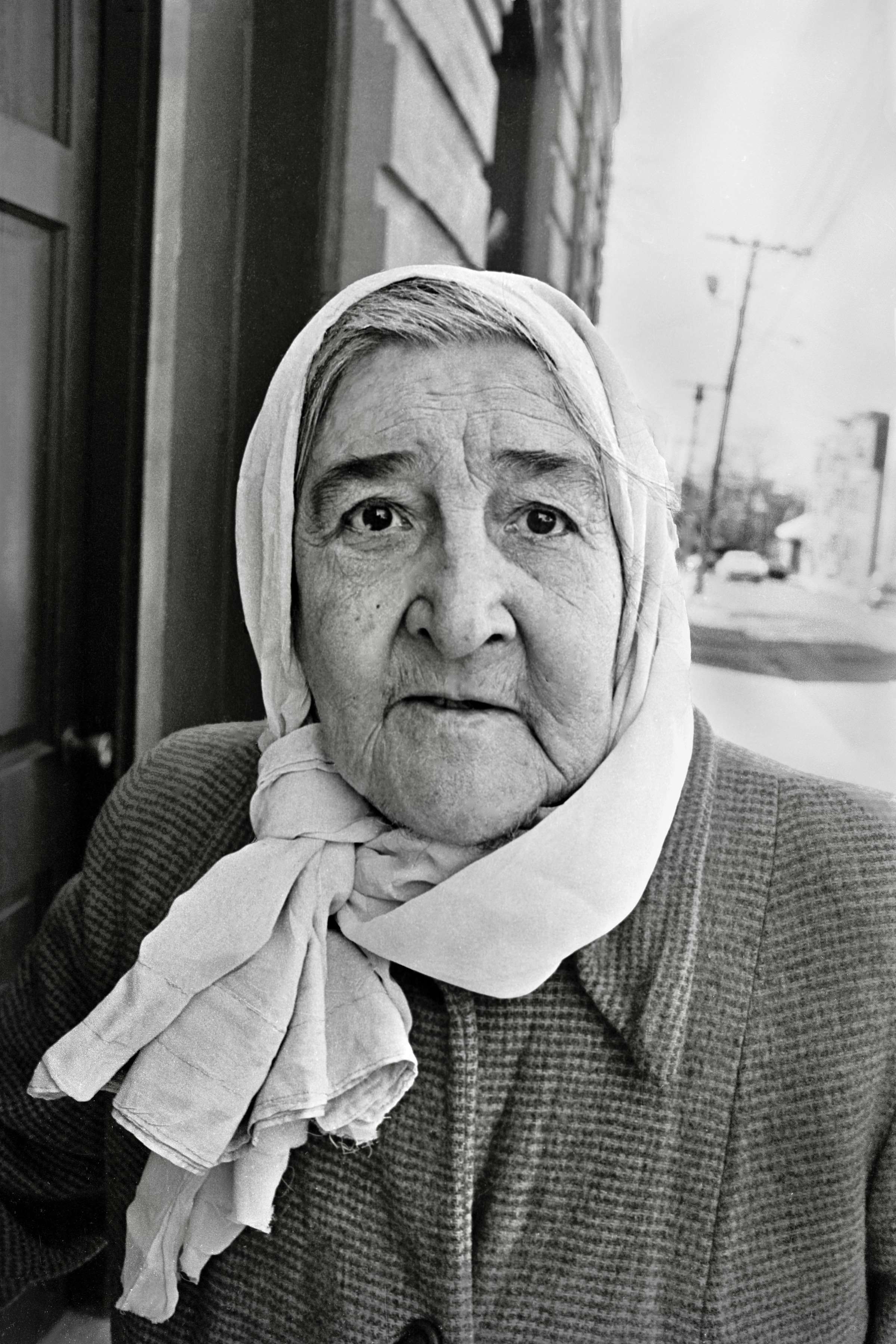 Black-and-white close portrait of an older woman wearing a kerchief.